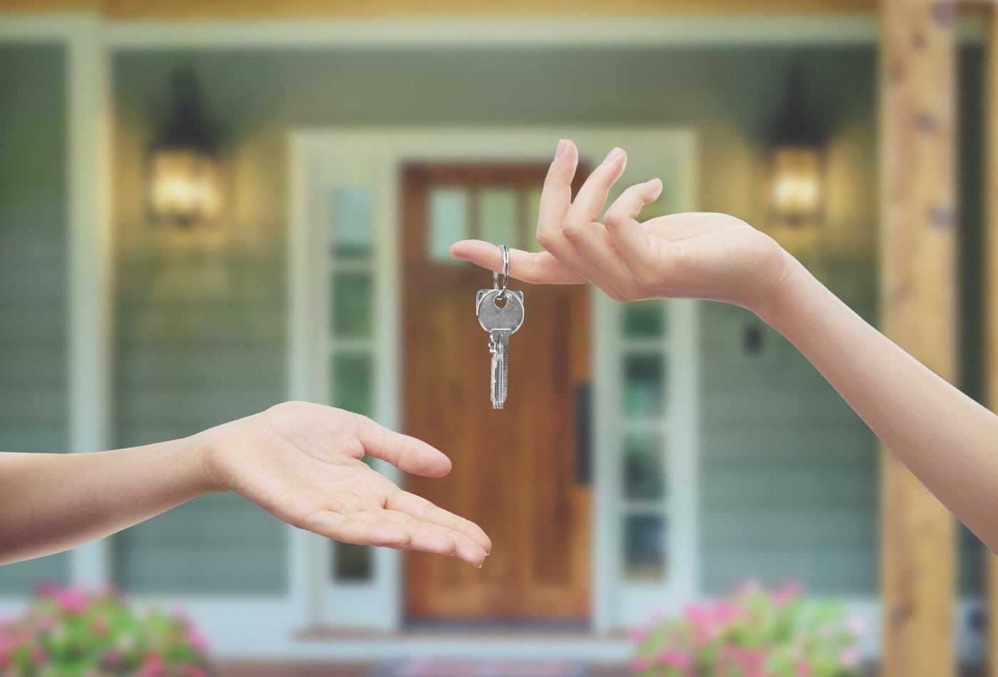 house key exchanging hands in front of home background
